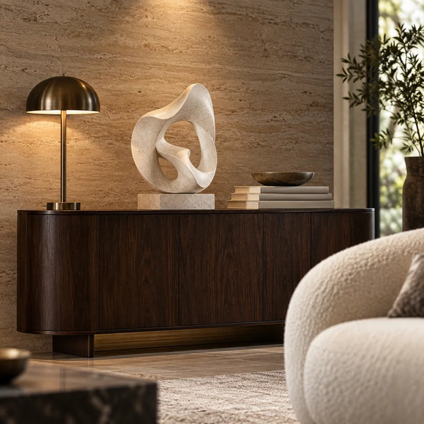 Sculptural decor and a bronze lamp on a dark walnut console